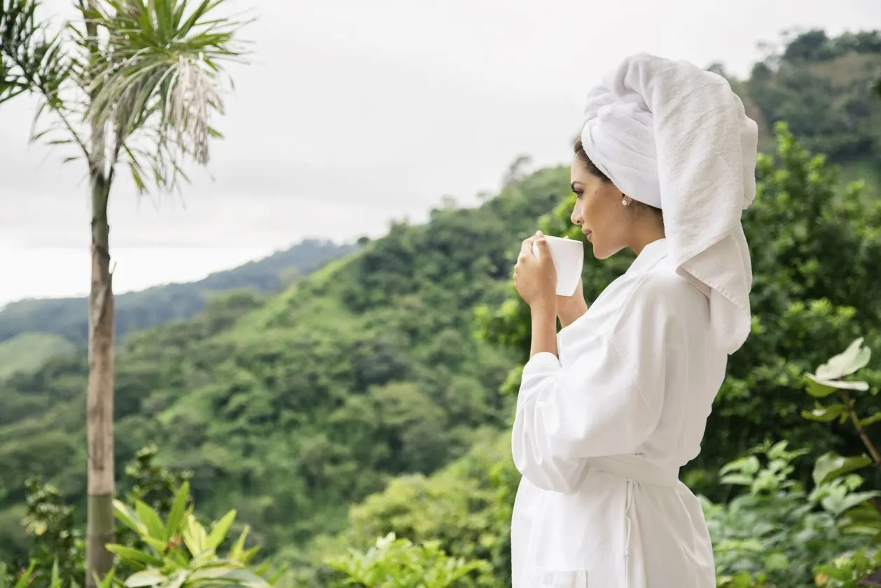 the retreat costa rica premium room woman in robe sipping morning coffee solo wellness retreat
